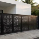 Pagar rumah minimalis modern dengan hollow galvanis coating hitam dan motif laser cutting, berdiri di atas pondasi beton dengan celah drainase